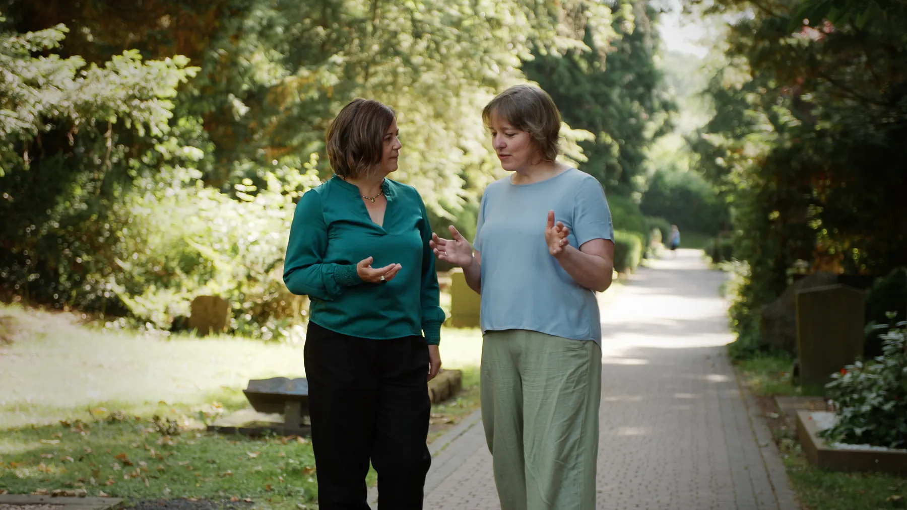 Kathy Pithan und Judith im Gespräch auf einem Friedhofsweg